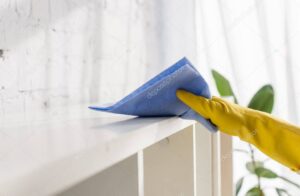 Cropped view of person in rubber glove cleaning cupboard with rag at home