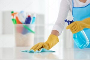 Housewife wiping table with spray