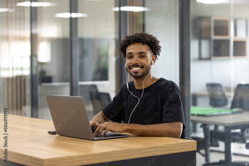 Jovem sorrindo com computador e fones de ouvido