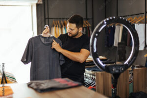 Pequenos negócios. Loja de roupas e acessórios de moda masculina. Dono usando o celular e criando conteúdo para as redes sociais.