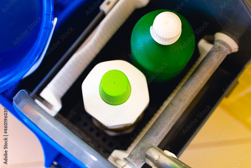 Produtos desinfetantes. Duas garrafas de produtos de limpeza em foto de perto que estão dentro de um carrinho de limpeza de cor azul. Higiene, Limpeza doméstica, água sanitária, desinfetante.