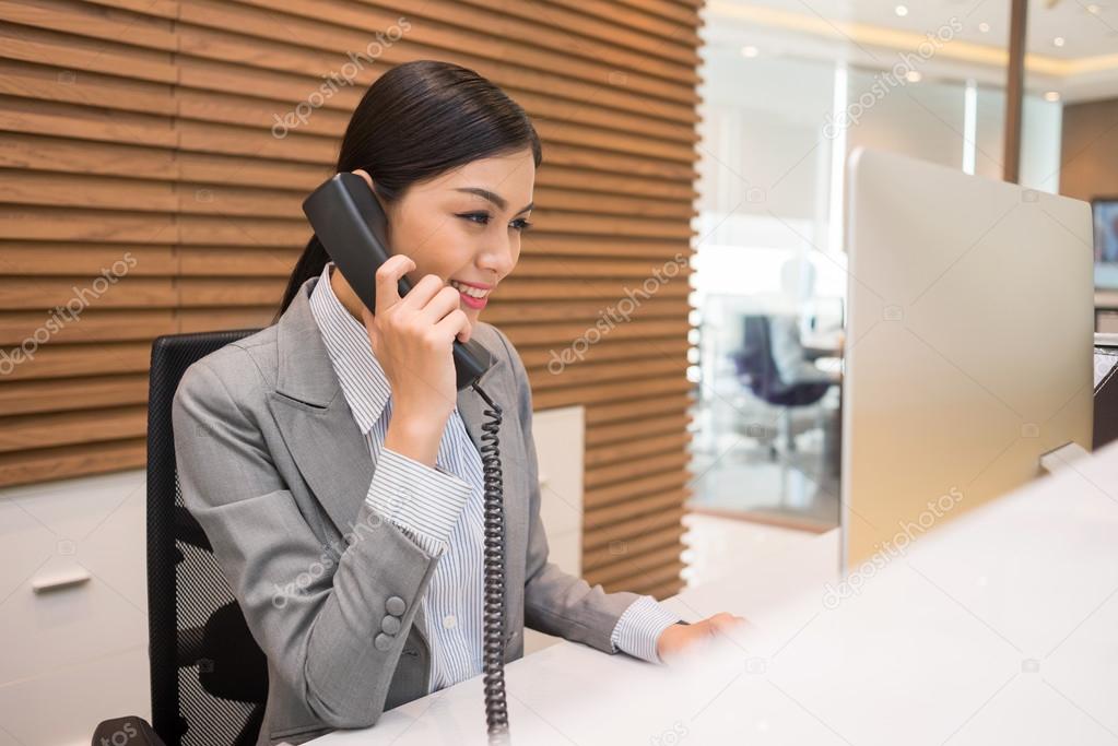 Vietnamese receptionist talking on telephone