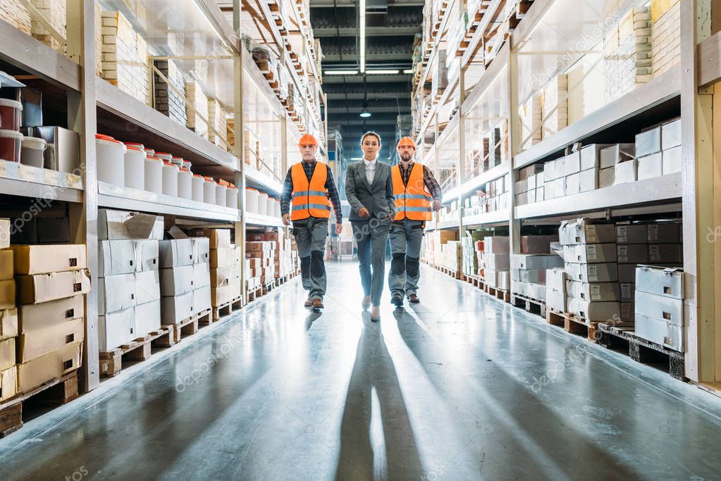 workers and inspector going along the corridor in storehouse