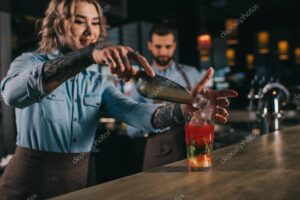 bartender adding ice into alcohol drink at bar