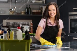 Beautiful cheerful brunette woman in gloves cleaning modern kitchen