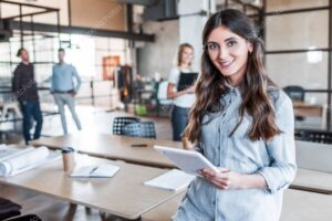 beautiful young businesswoman using digital tablet and smiling at camera in office