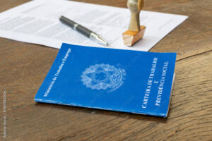 Brazilian Work Card with stamp, pen and paper on the rustic table. Employment contract concept. Portuguese text "Labor and Social Security Card". Selective focus.