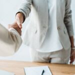 cropped view of recruiter and employee shaking hands while standing  in office