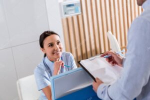 Smiling nurse sitting at workplace and talking to doctor