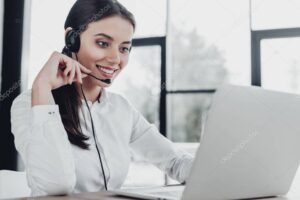 beautiful female call center worker with headphones and laptop sitting at workplace