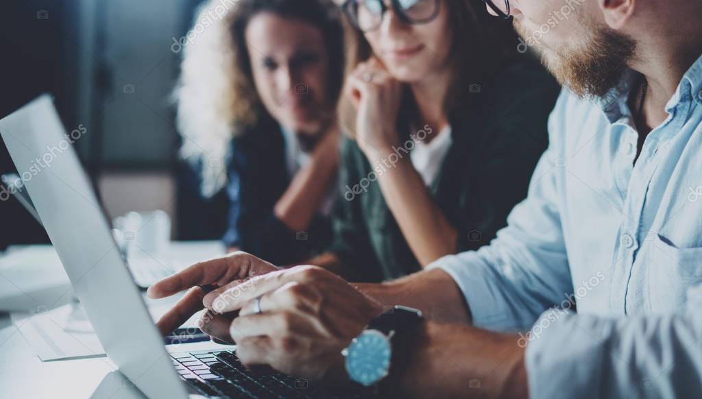 Concept of teamwork process at office.Young team working together at night modern office loft.Blurred background.Horizontal.Cropped.