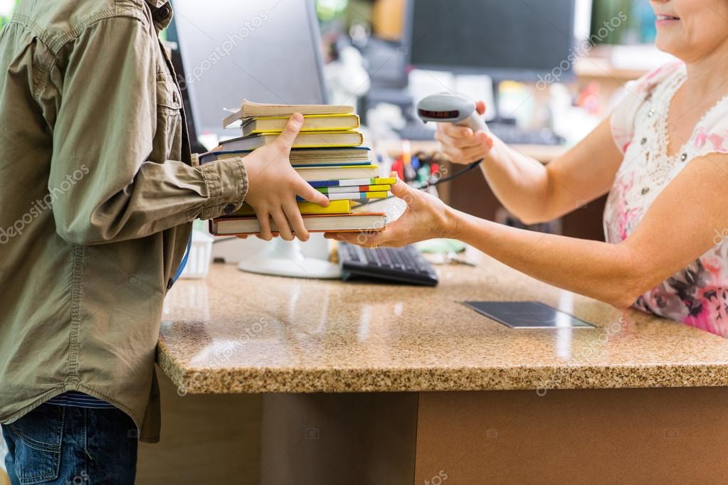 Schoolboy Holding Books At Library Counter