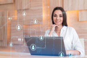 Attractive businesswoman in white shirt at workplace working with laptop to hire new employees for international business consulting. HR, social media hologram icons over office background