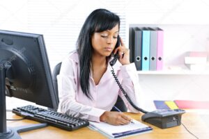 Serious black businesswoman on phone at desk