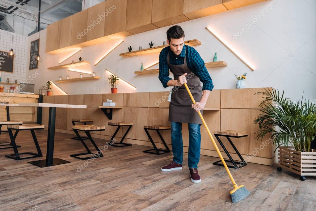 worker cleaning floor with sweep