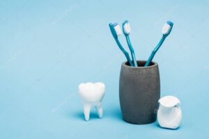 Toothbrushes near dental floss and tooth model on blue background