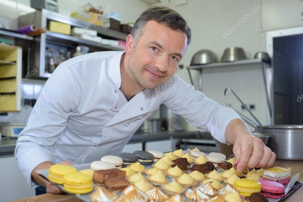 Baker holding tray of cakes