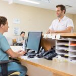 Nurse And Patient Conversing At Reception Desk