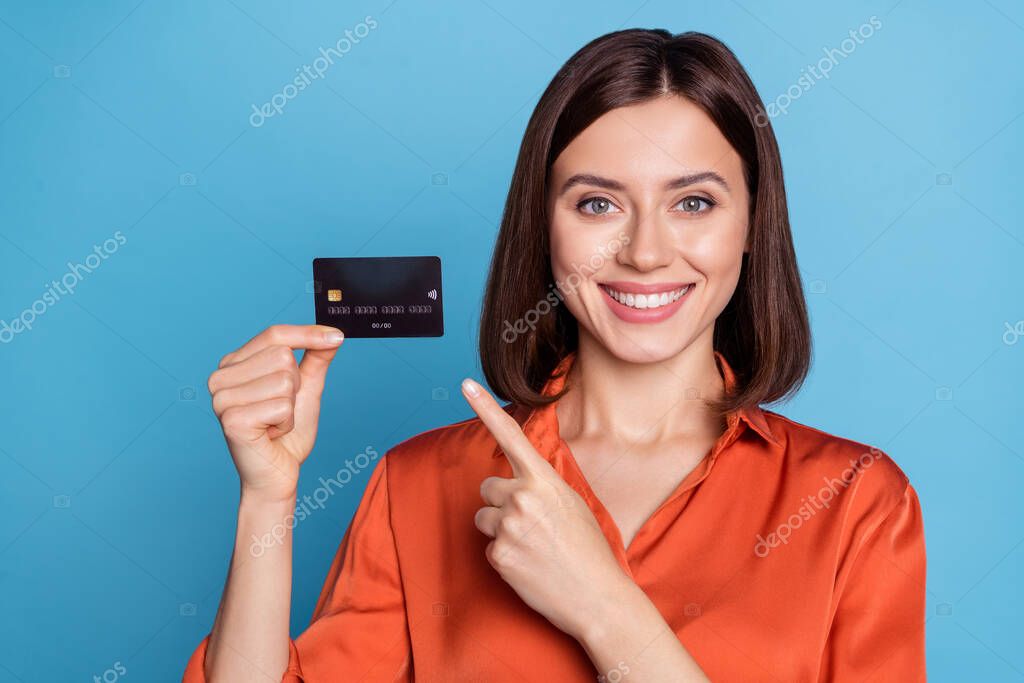Portrait of attractive cheerful girl holding in hand demonstrating bank card isolated over bright blue color background